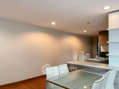 Modern dining area with sleek glass table and open kitchen layout