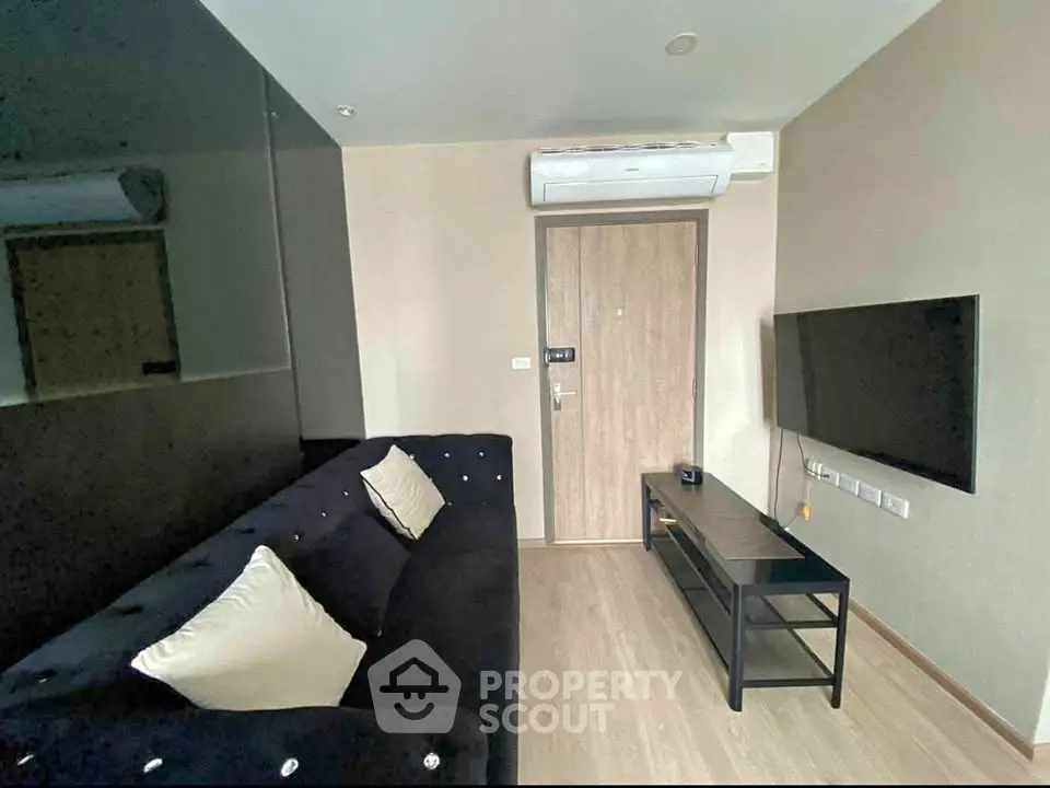 Modern living room with sleek black sofa and wall-mounted TV, perfect for cozy relaxation.
