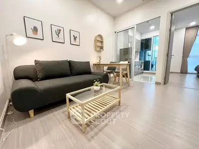 Modern living room with sleek black sofa and stylish decor in open-concept apartment.