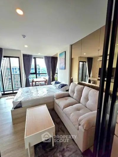 Modern studio apartment with cozy living area and large windows