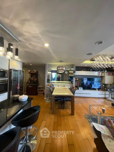 Spacious open-plan living area with modern kitchen and dining space, featuring hardwood floors and stylish lighting.