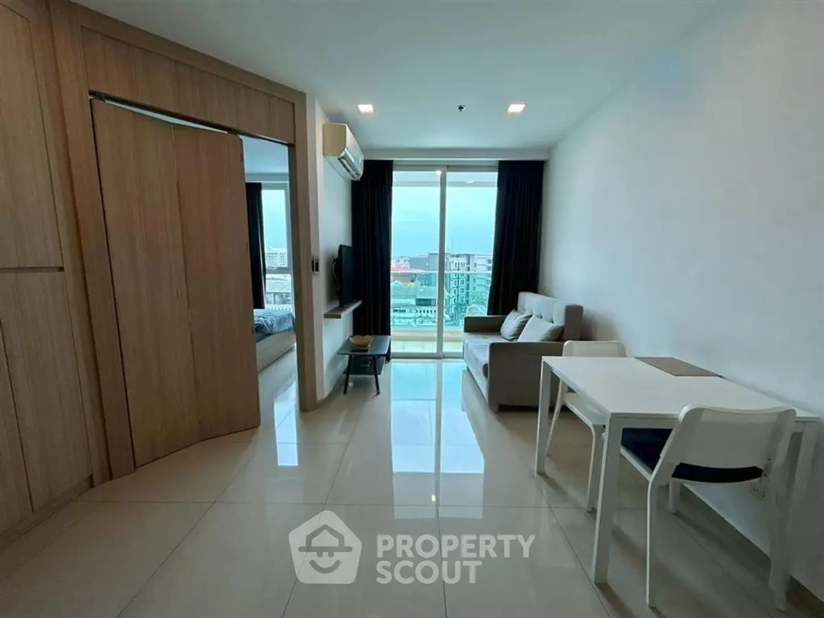 Modern living room with sleek furniture and city view from balcony.