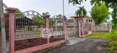 Elegant gated entrance to a luxurious property with lush greenery and palm trees.