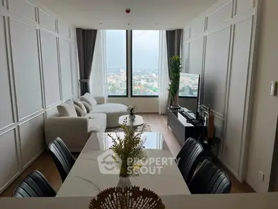 Modern living room with large window and city view, featuring elegant furniture and stylish decor.