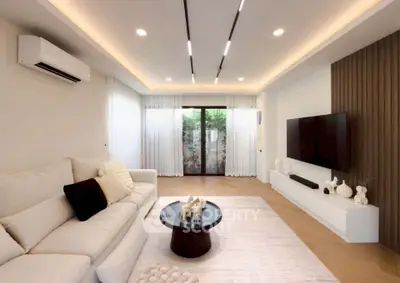 Modern living room with elegant decor, featuring a cozy sofa, sleek TV setup, and ambient lighting.