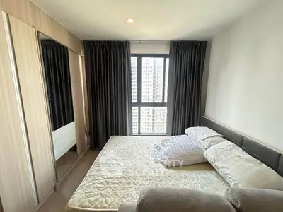 Spacious bedroom with large window and modern furnishings in urban apartment