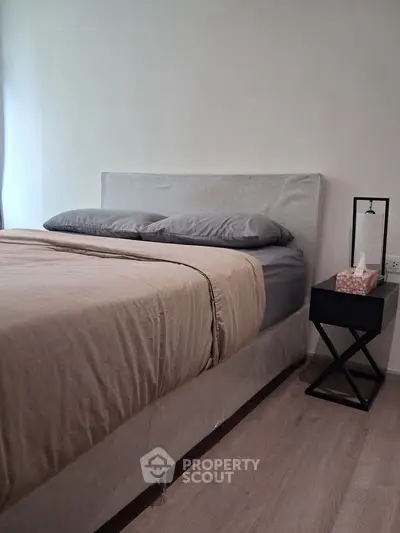 Cozy bedroom with modern bed and stylish nightstand in a serene setting.