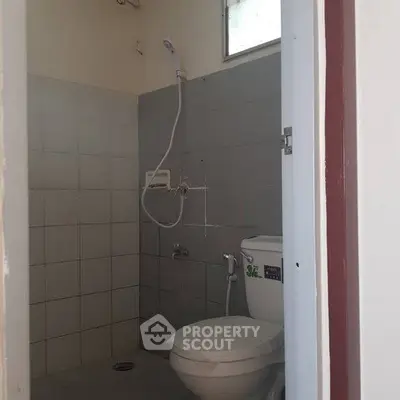 Compact bathroom with shower and toilet in minimalist design.