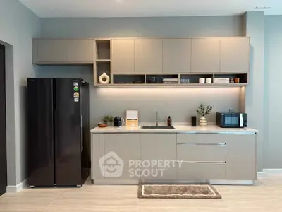 Modern kitchen with sleek cabinetry and appliances, featuring a black fridge and stylish decor.