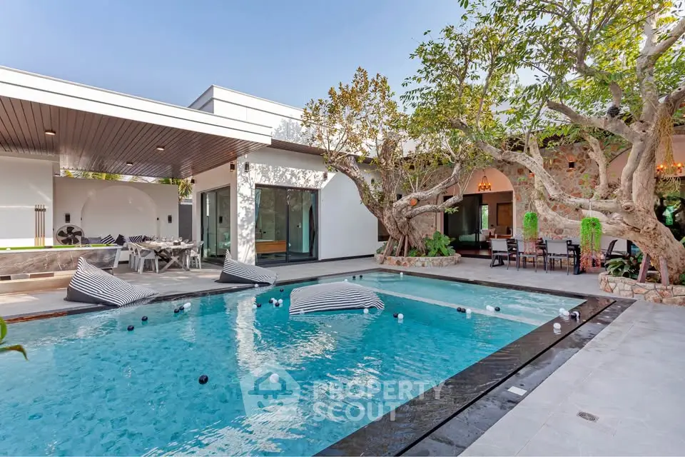 Luxurious modern villa with stunning pool and outdoor dining area, perfect for relaxation and entertainment.