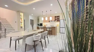 Modern kitchen with open layout and elegant dining area featuring stylish lighting and sleek design.