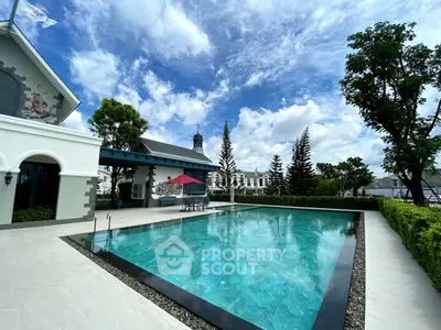 Luxurious outdoor pool with clear blue water and elegant surroundings under a bright sky.