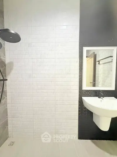 Modern bathroom with sleek black shower and white sink on textured wall.