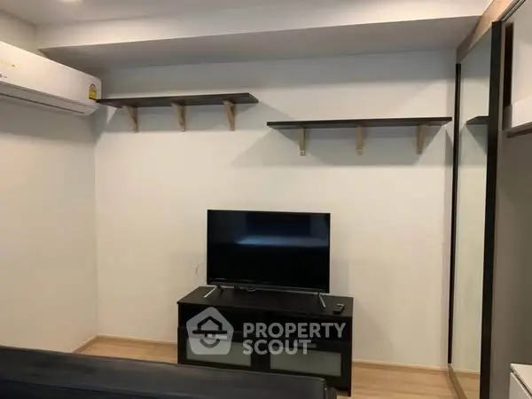 Modern living room with sleek TV setup and wall-mounted shelves