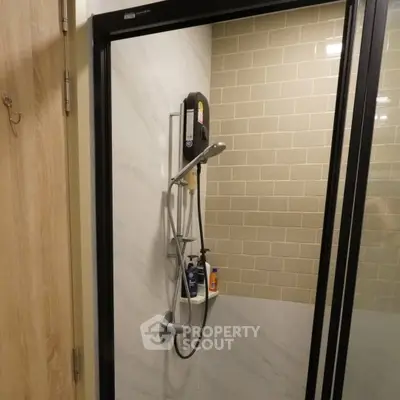 Modern bathroom shower with glass door and tiled walls in a stylish apartment.
