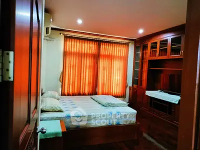 Cozy bedroom with wooden furniture and warm lighting, featuring a comfortable bed and built-in storage.