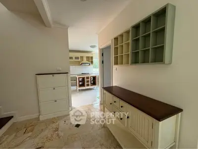 Spacious entryway leading to a bright kitchen with open shelving and modern cabinetry.