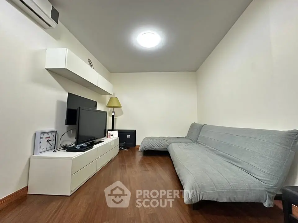 Modern living room with sleek furniture and wooden flooring, featuring a cozy ambiance.