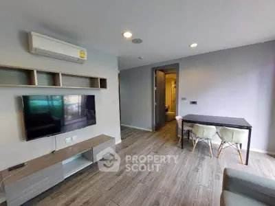Modern living room with sleek TV setup and dining area in stylish apartment.