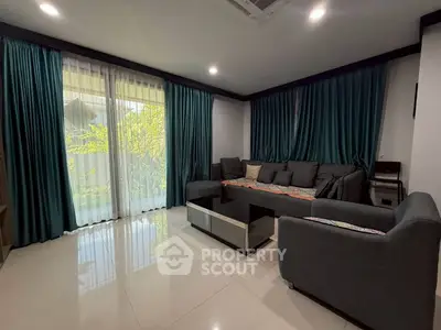 Spacious living room with modern furniture and large windows offering garden views.
