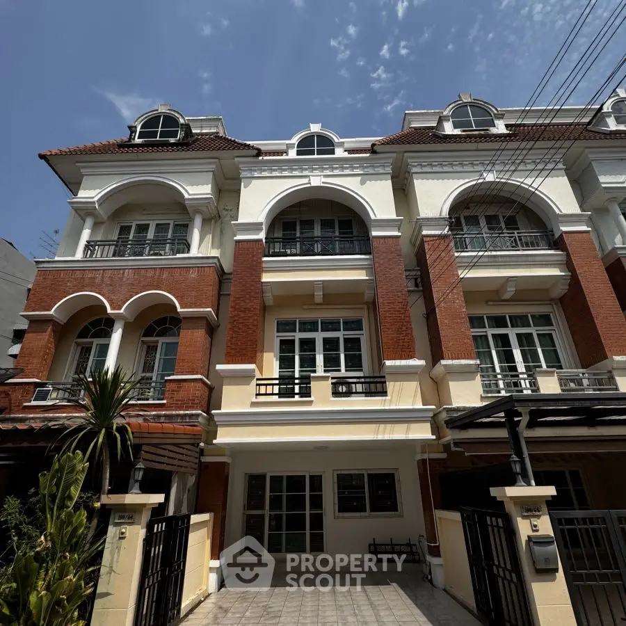 Elegant multi-story townhouse with classic architecture and spacious balconies under a clear blue sky.