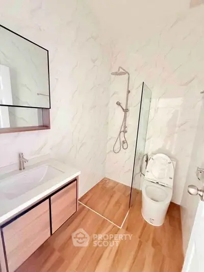 Modern bathroom with sleek fixtures and glass shower partition in a stylish real estate property.