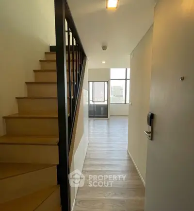Modern duplex apartment entrance with wooden stairs and bright living area