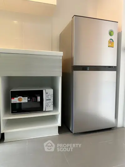 Modern kitchen with sleek fridge and microwave in compact layout.