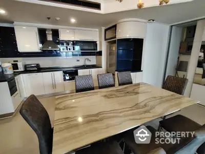 Modern kitchen with elegant dining table and chairs, featuring sleek cabinetry and built-in appliances.