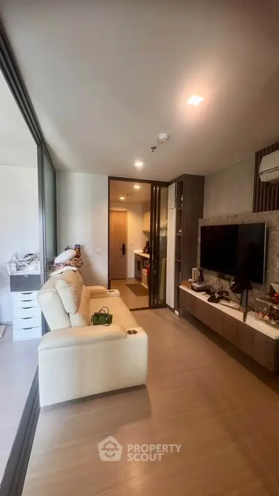Modern living room with sleek design and cozy seating area, featuring a large TV and stylish decor.