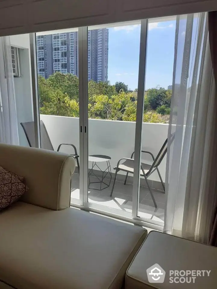 Chic apartment balcony with modern seating and lush green view