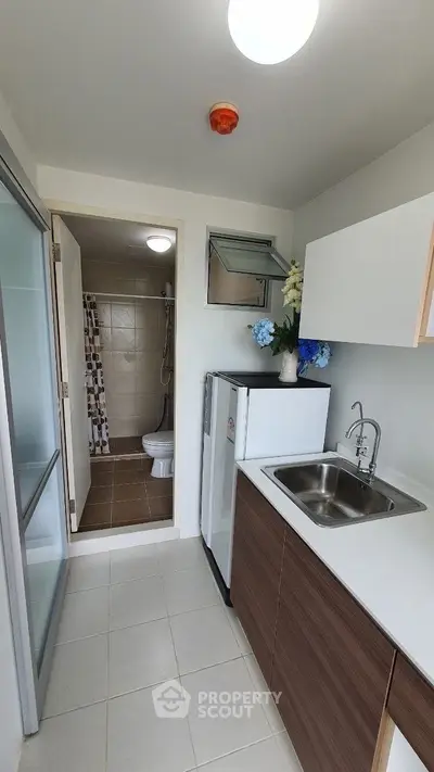 Compact kitchen with sleek cabinetry and adjacent bathroom, ideal for modern living.