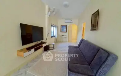 Spacious living room with modern TV setup and cozy seating in a stylish apartment.