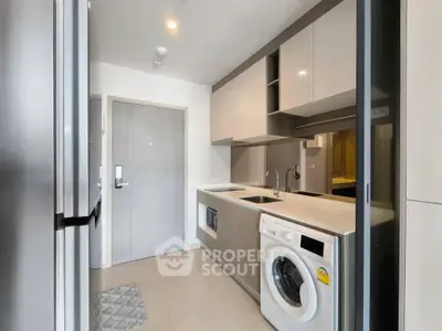 Modern kitchen with sleek cabinetry and built-in washing machine in a stylish apartment.