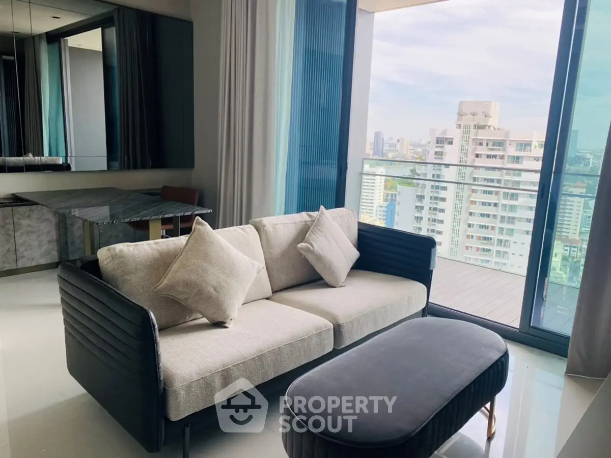 Modern living room with plush sofa and city view from large balcony window.
