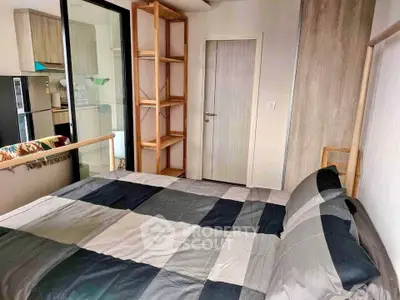 Cozy bedroom with modern decor and adjacent kitchen area in a compact apartment.
