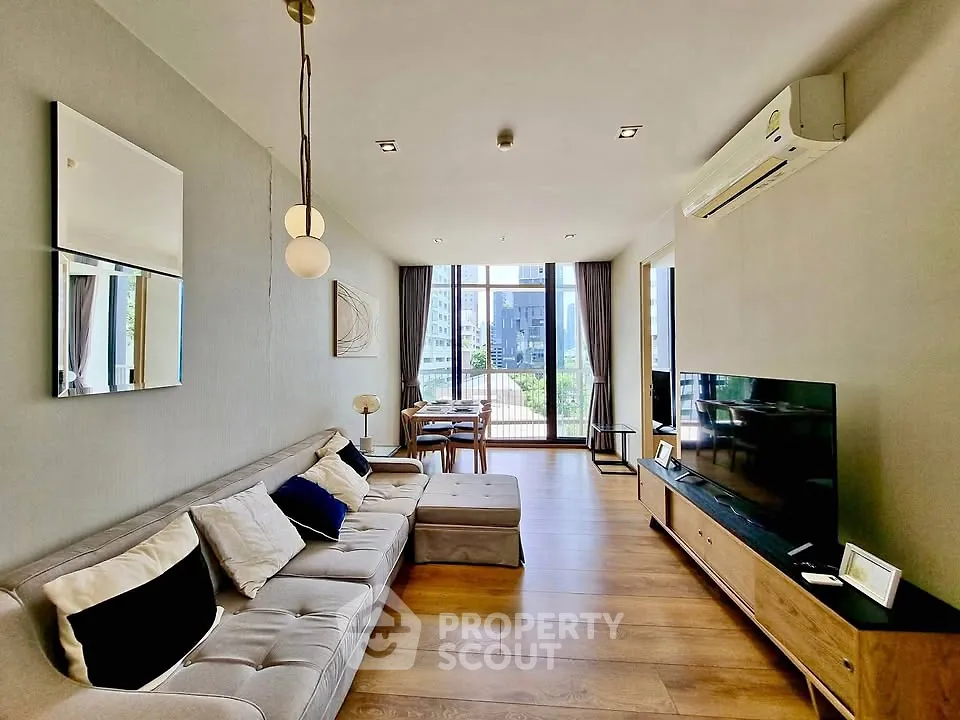 Spacious modern living room with large windows and stylish decor in a high-rise apartment.
