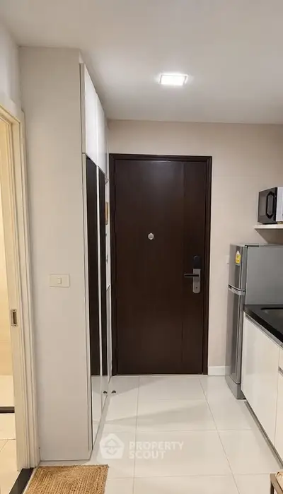Modern apartment entrance with sleek kitchen and stainless steel fridge