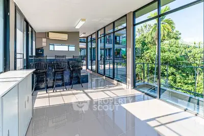 Spacious modern living room with floor-to-ceiling windows and lush garden view.
