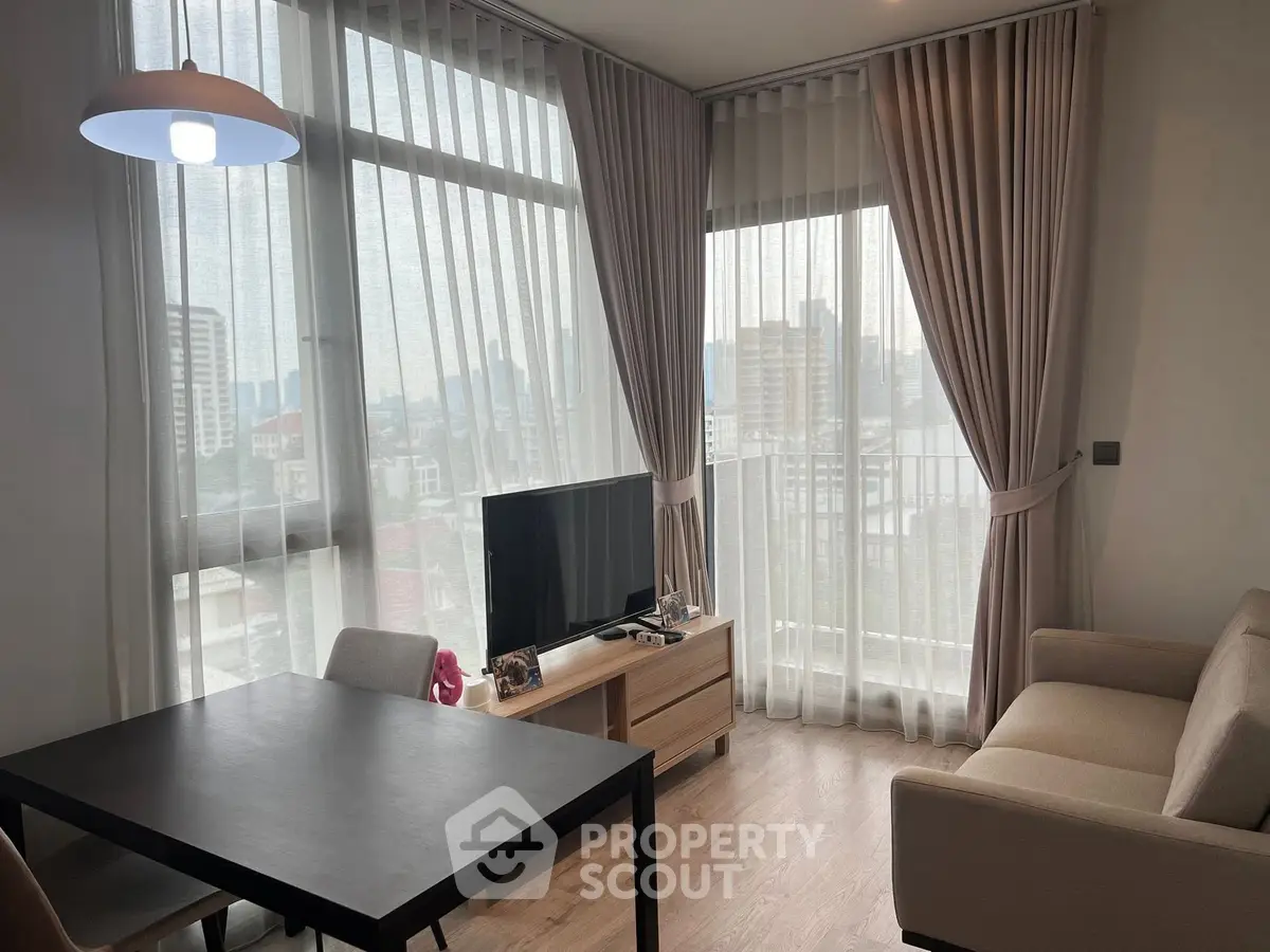 Modern living room with large windows and city view, featuring a cozy sofa and sleek dining table.