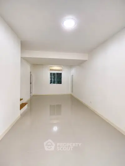 Spacious and bright living room with glossy tiled floors and modern lighting.