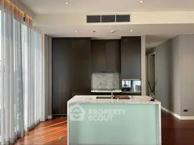 Luxurious modern kitchen with marble island and sleek cabinetry in high-end apartment.