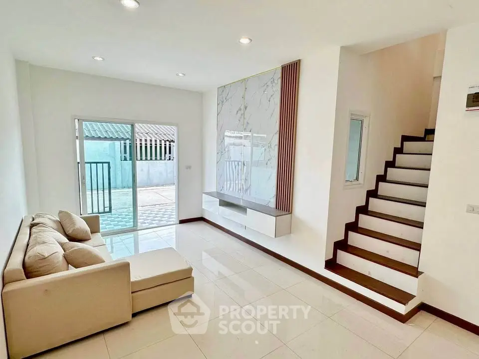 Modern living room with sleek staircase and cozy sofa in bright, airy space.