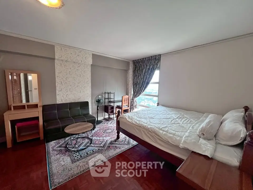 Spacious bedroom with elegant decor and city view, featuring a cozy seating area and stylish furniture.