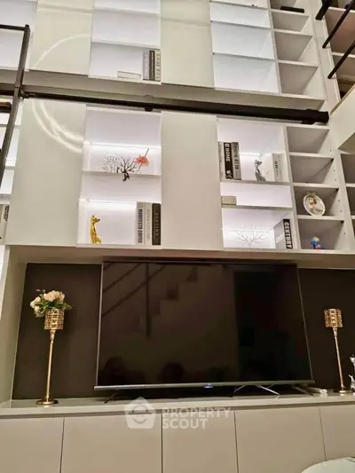 Luxurious living room with high ceiling, elegant shelving, and modern TV setup.