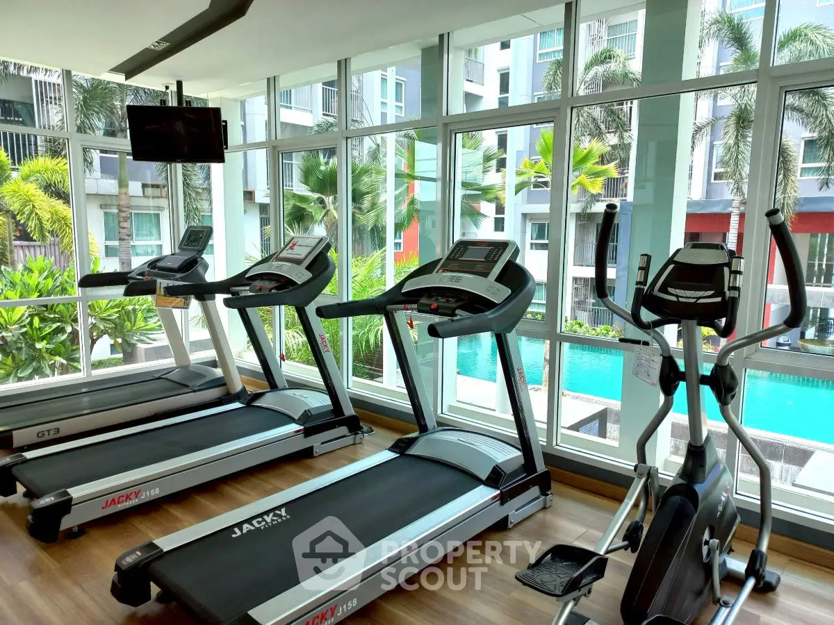 Modern gym with treadmills and pool view in luxury apartment complex