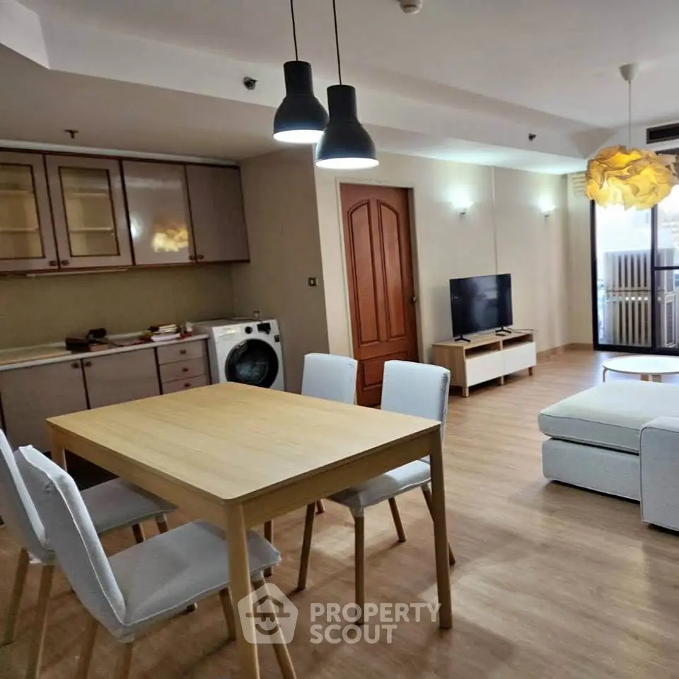 Modern open-plan living room with dining area and washing machine in stylish apartment.