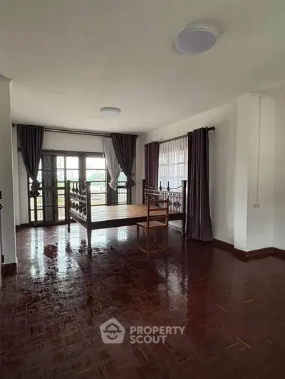 Spacious living room with wooden flooring and large windows for natural light.