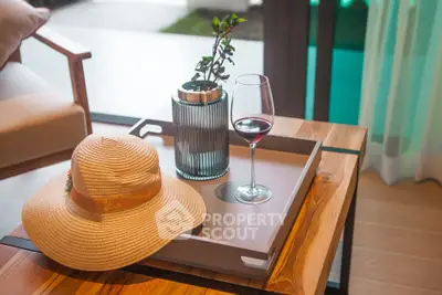 Stylish living room corner with wooden table, elegant decor, and wine glass near window.
