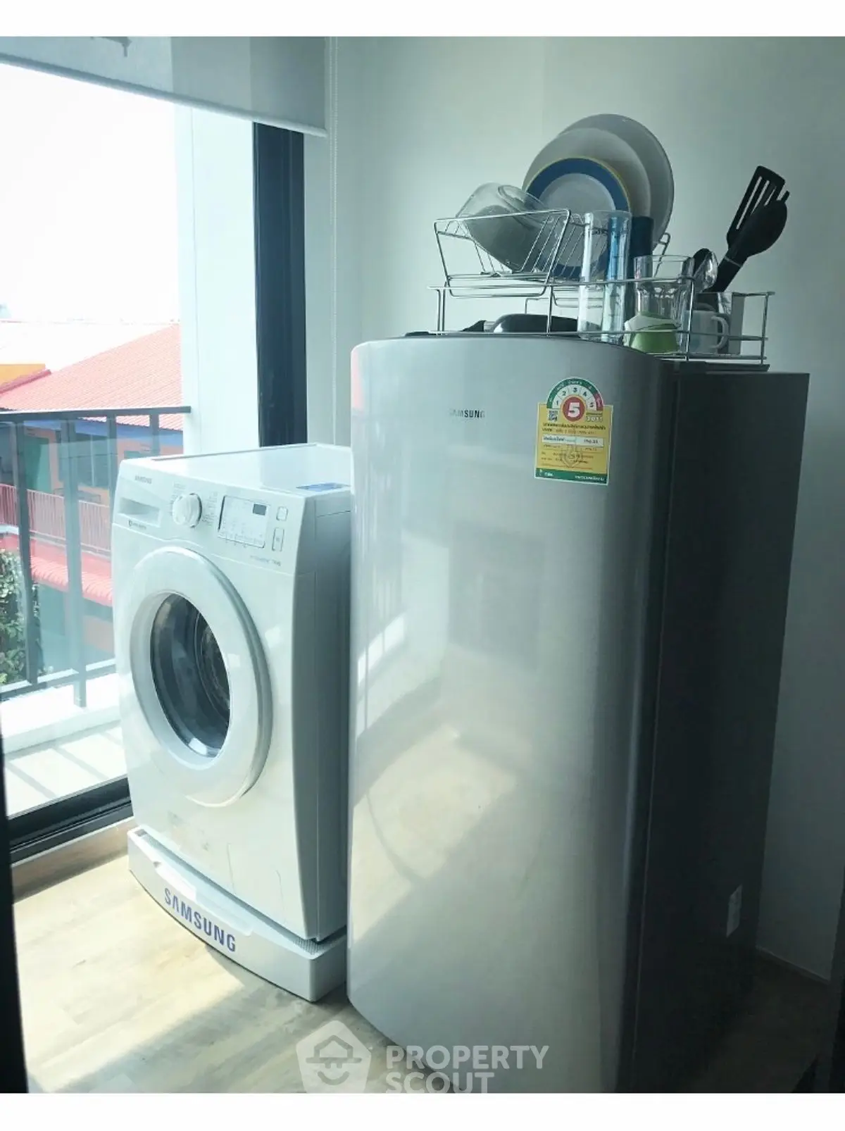 Modern laundry area with washing machine and compact fridge in bright apartment.